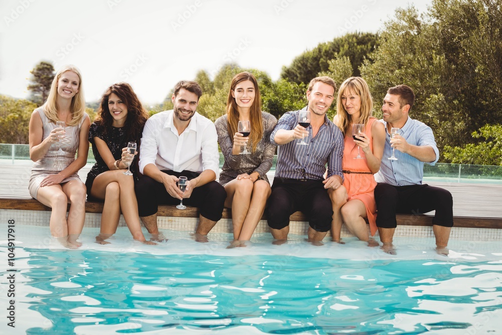Young people sitting by swimming pool Young people sitting by swimming pool