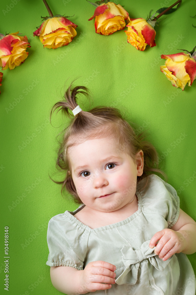 Fototapeta premium pretty little girl lying on green blanket with yellow roses