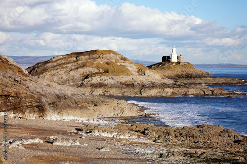 Mumbles with it's lighthouse as seen from Bracelet Bay on the Gower Peninsular, West Glamorgan, Wales, UK, a popular Welsh coastline attraction for tourist visitors photo