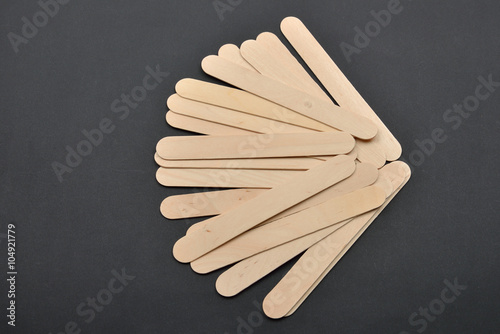 Picture of many wooden spatulas for wax depilation on black back photo