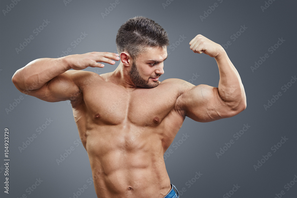 Surprised shirtless muscular man pointing to his strained bicep 