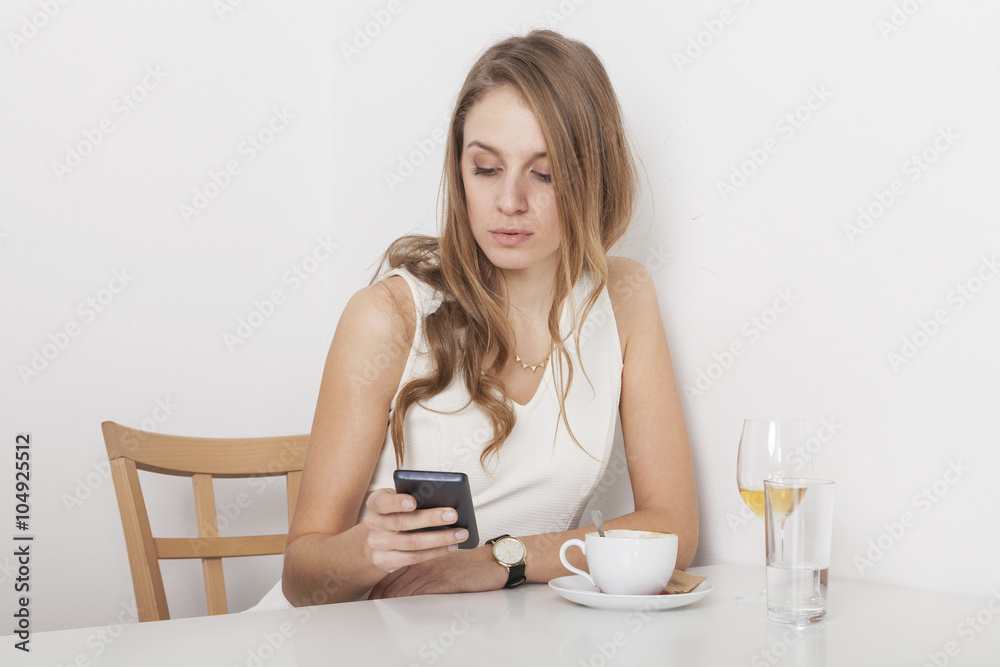 Blondine sitzt im Café und schreibt eine Nachricht auf Ihrem Ha Blondine sitzt im Café und schreibt eine Nachricht auf Ihrem Ha