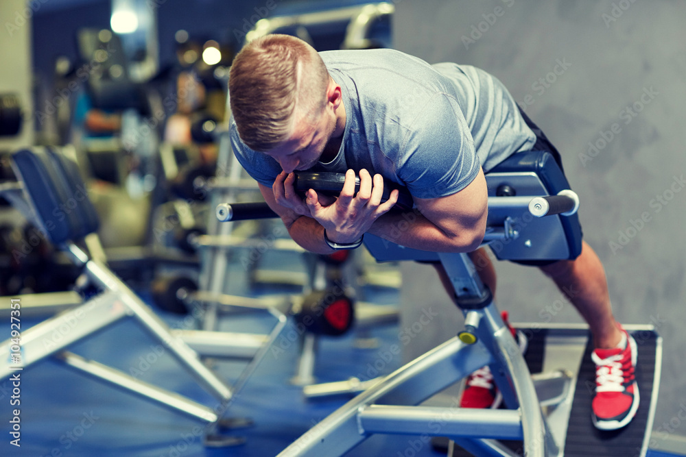 young man flexing back muscles on bench in gym young man flexing back muscles on bench in gym