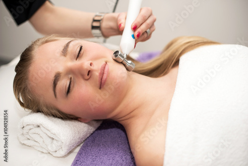 Young woman lying on massage table receiving face massage. Beaut