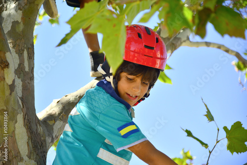 Bopy with red helmet climbing a tree photo