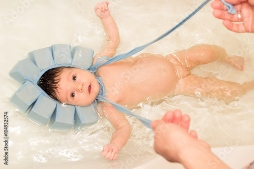 Baby girl swiming in the bath with special blue swiming mutch Fototapeta