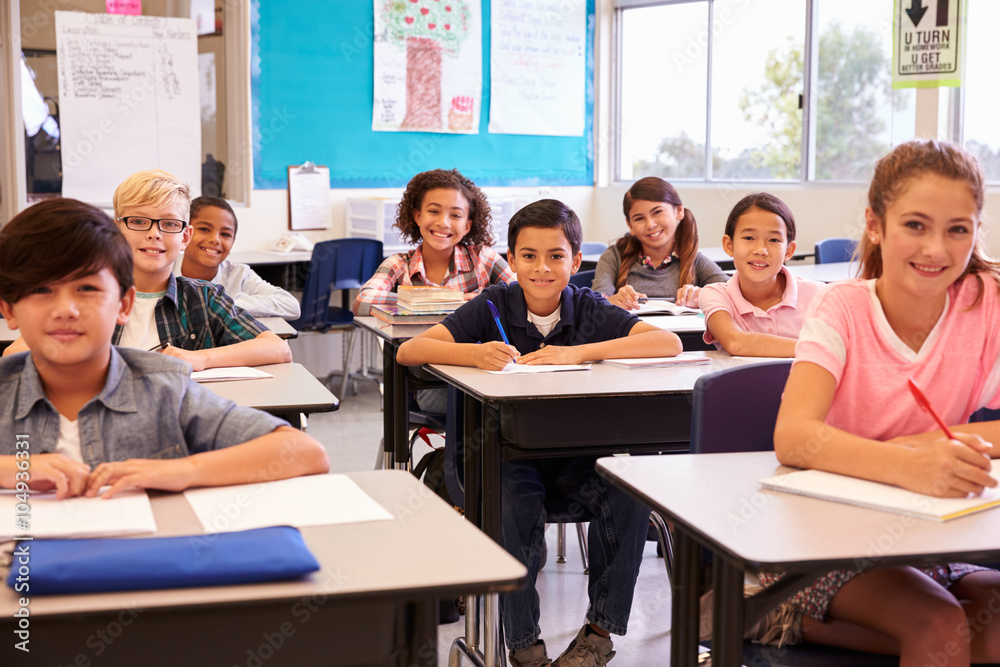 Smiling elementary school kids sitting at desks in classroom Smiling elementary school kids sitting at desks in classroom