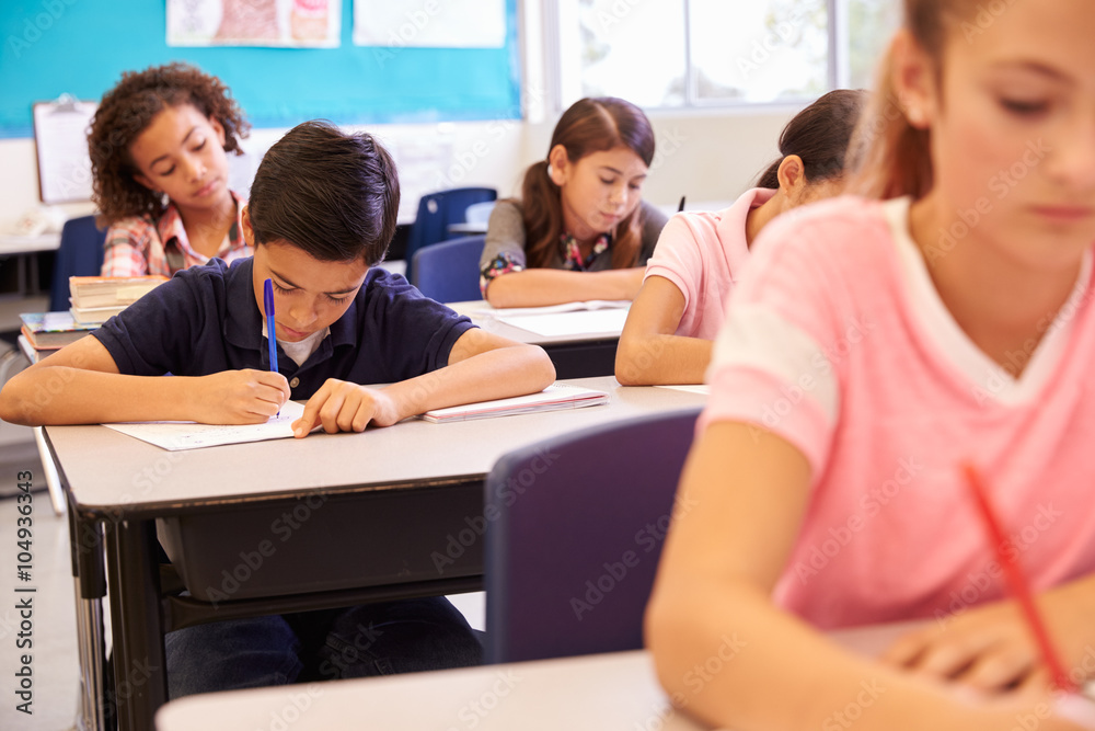 Elementary school kids working at their desks in a classroom Elementary school kids working at their desks in a classroom