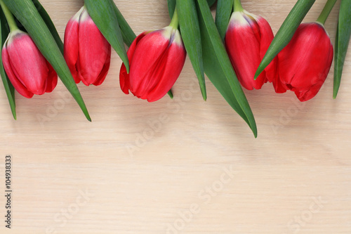 five red tulips on wooden table