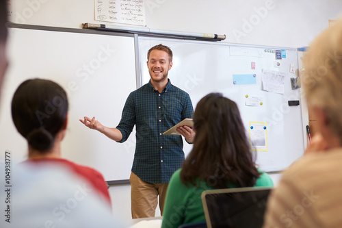 Male teacher listening to students at adult education class photo