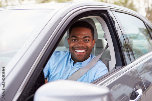 African American male driver looking to camera through car windo