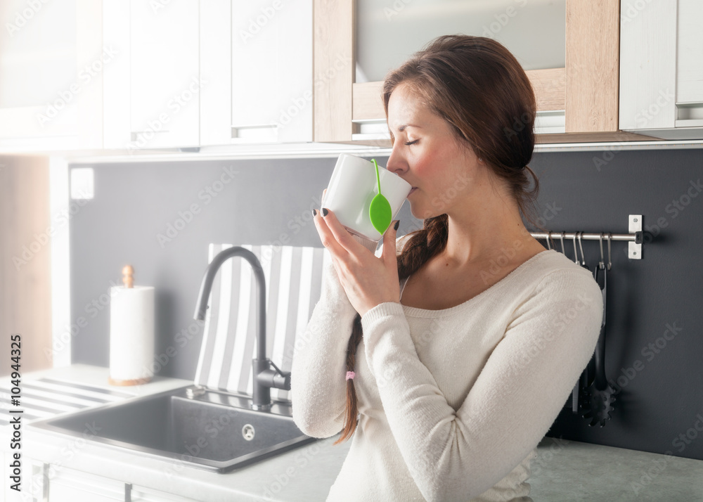 Woman with cup of tea in kitchen Woman with cup of tea in kitchen