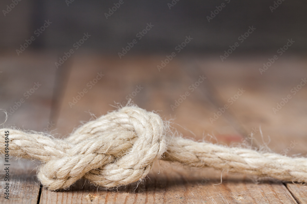 Old frayed rope twisted and tied in a bundle on a rough wooden background