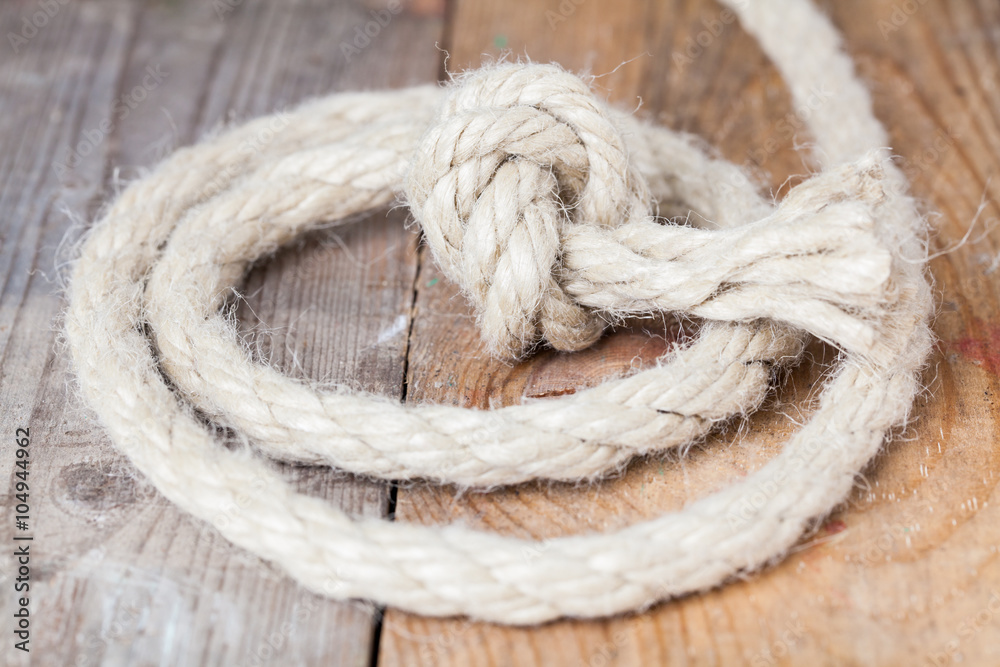 Old frayed rope twisted and tied in a bundle on a rough wooden background