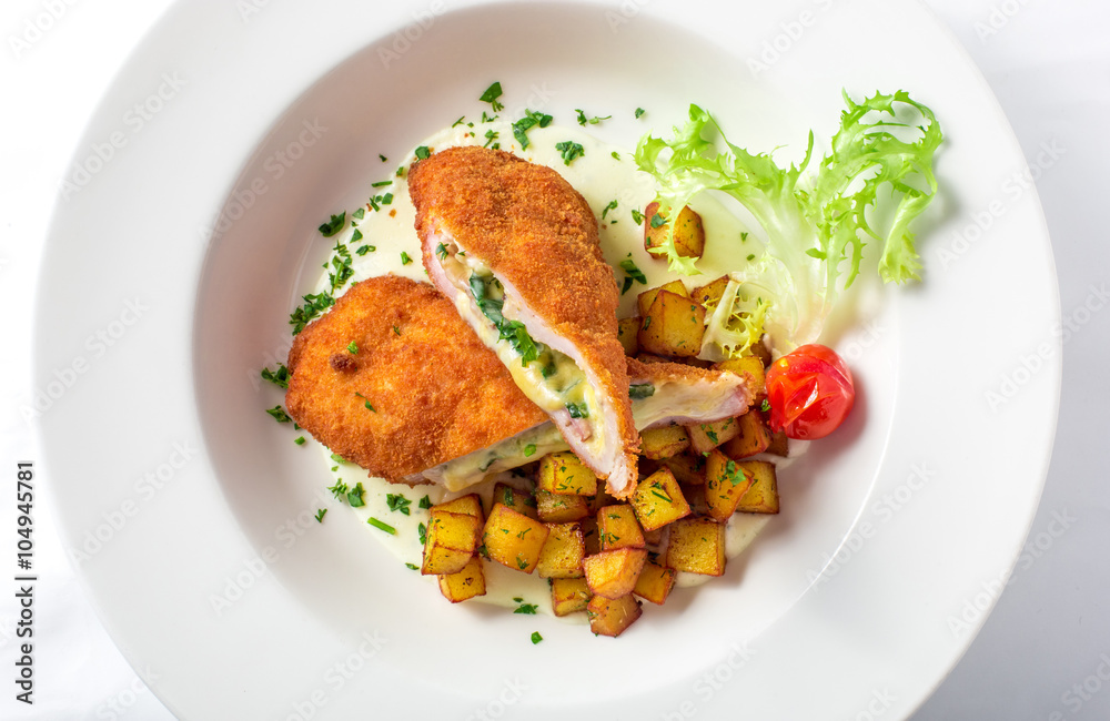Cutting cordon bleu with cheese, turkey, crackers crumbs, potatoes.