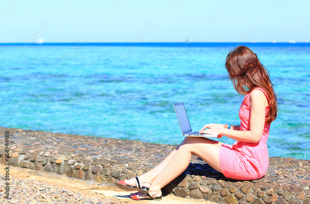 freelancer woman working on her laptop computer at the sea