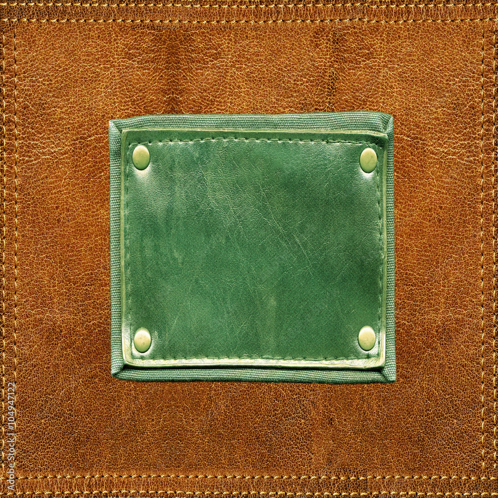 Fototapeta premium Green blank leather label stitched onto orange leather surface