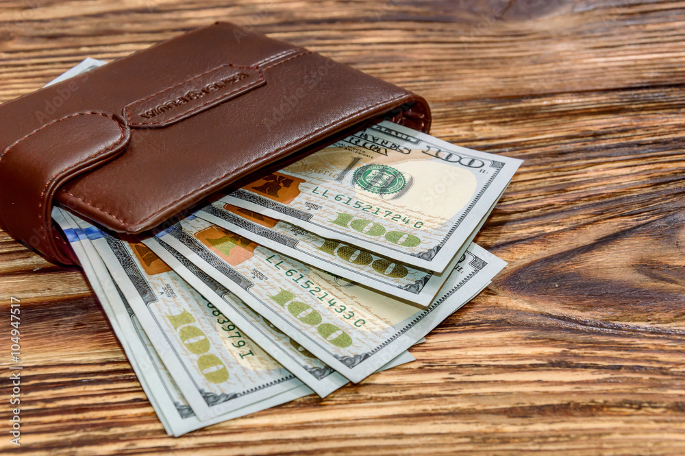 Wallet with US Dollars on wooden background Wallet with US Dollars on wooden background