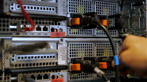 IT technician inserts power cord in server