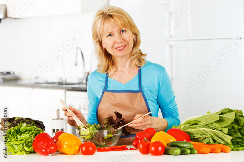 Woman preparing salad in the kitchen.