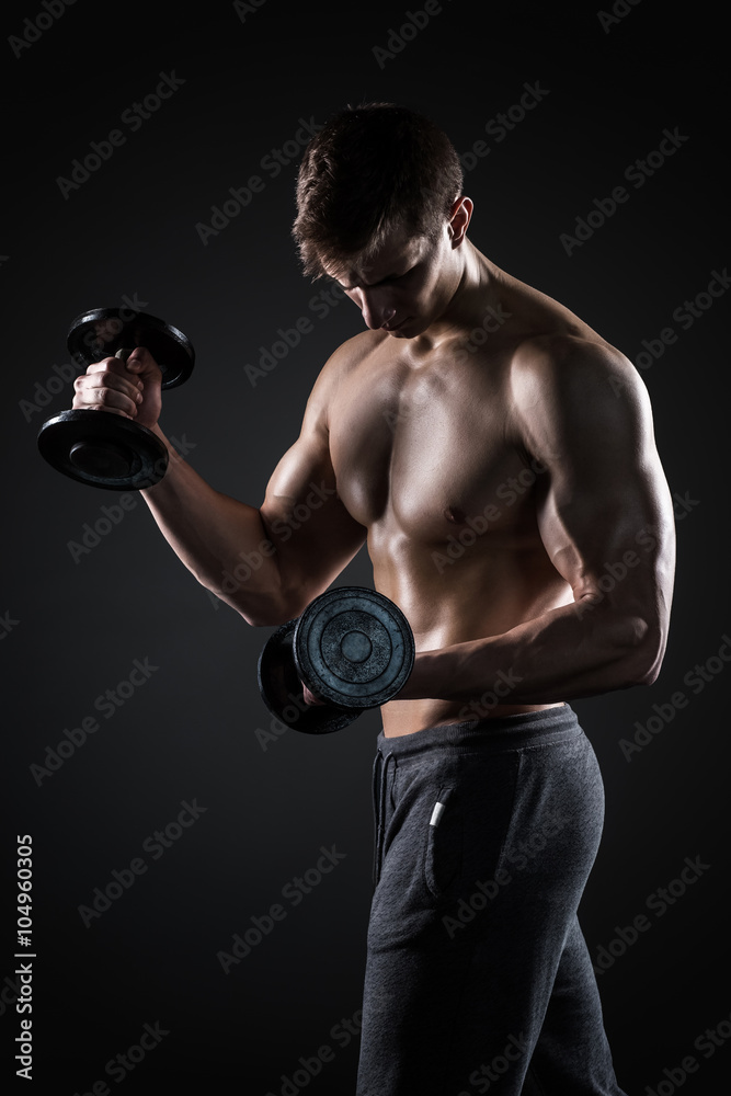 Athletic man showing muscular body and doing exercises with dumbbells