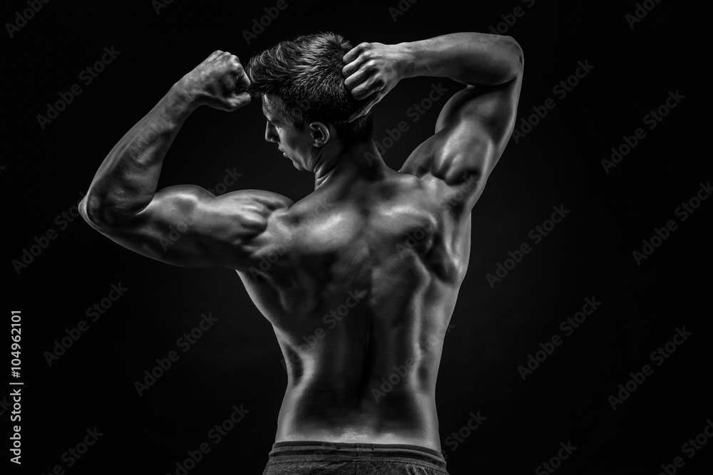 Healthy muscular young man showing back and biceps muscles