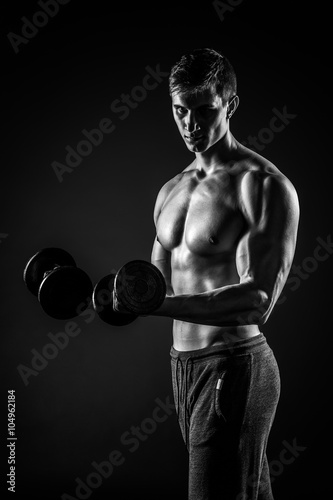 Handsome man showing perfect body with dumbbells on black backgr © nazarovsergey