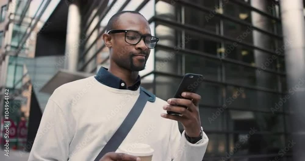 African American businessman walking through city using smart phone