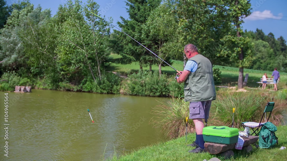 Fisher with fishing rod fishing on pond Fisher with fishing rod fishing on pond