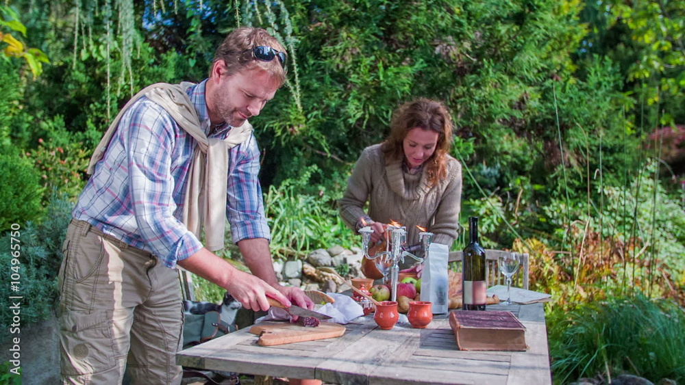 Couple preparing the food for a meal on the garden table Couple preparing the food for a meal on the garden table