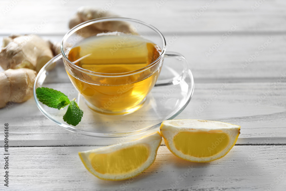 Glass cup of green tea with lemon and ginger root on wooden background Glass cup of green tea with lemon and ginger root on wooden background