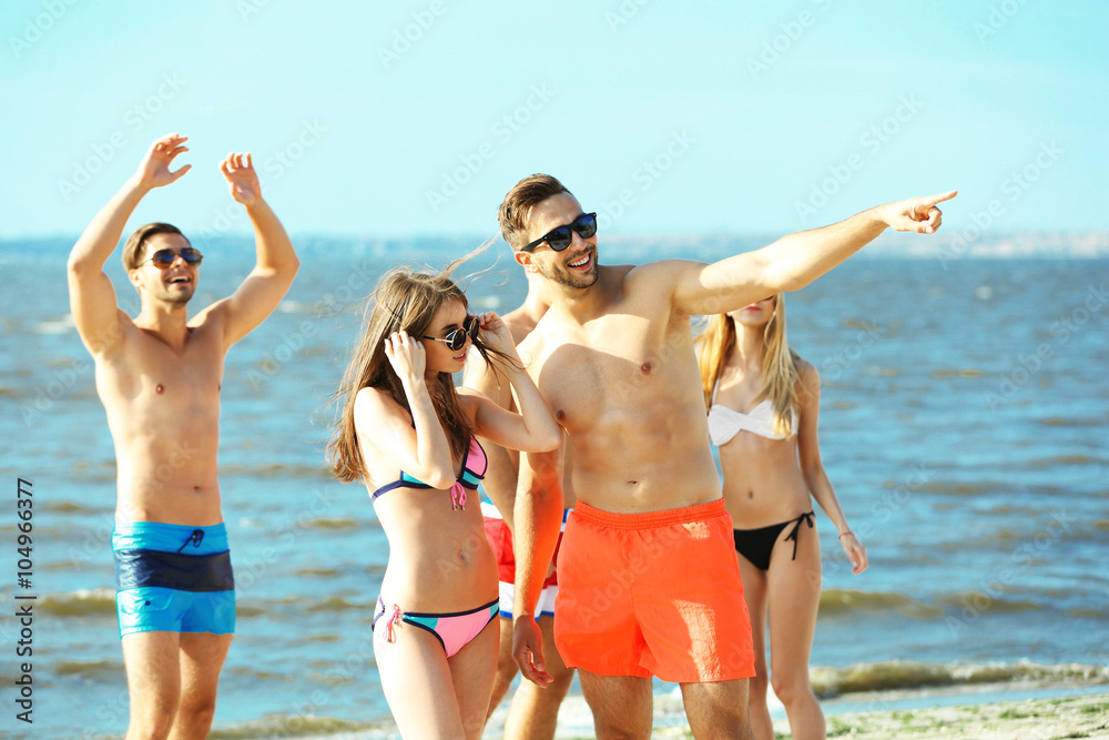 Happy couple and their playful friends relaxing at the beach, outdoors Happy couple and their playful friends relaxing at the beach, outdoors