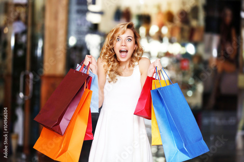 Beautiful young woman with bags in shopping center