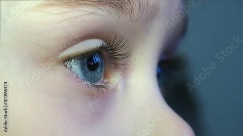 Close-up of little girl eyes watching TV with great interest