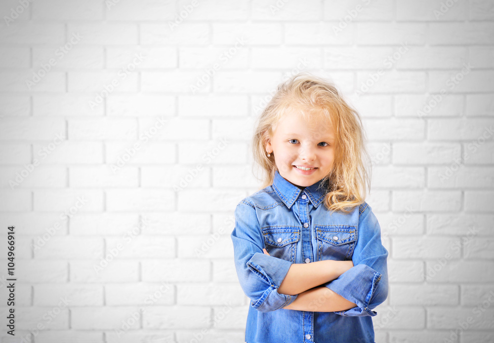 Little girl in jeans suit on a white brick wall background Little girl in jeans suit on a white brick wall background