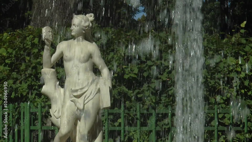 Античная статуя в Летнем саду Санкт-Петербурга, просматривающаяся сквозь брызги фонтана солнечным летним днём.