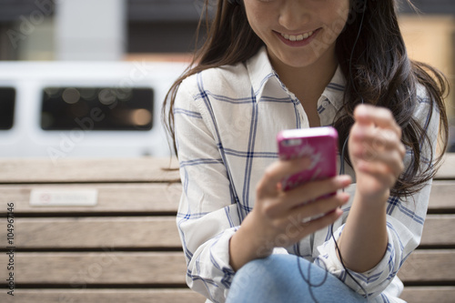 Young women are using a smart phone sitting on a bench #104967146