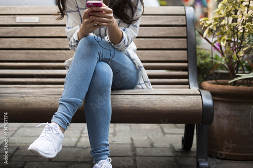 Young women are using a smart phone sitting on a bench #104967174