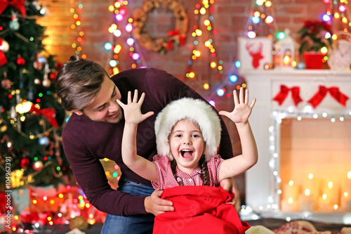 Funny little sister in Santa sack surprising her older brother on Christmas background © Africa Studio