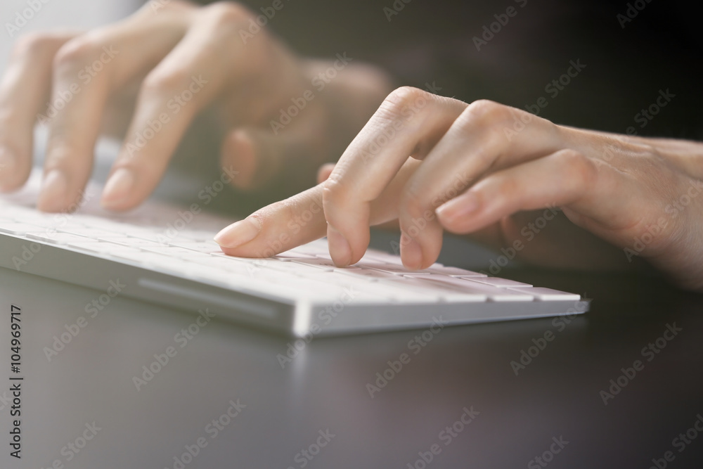 Female hands using keyboard on dark wooden table, close up Female hands using keyboard on dark wooden table, close up