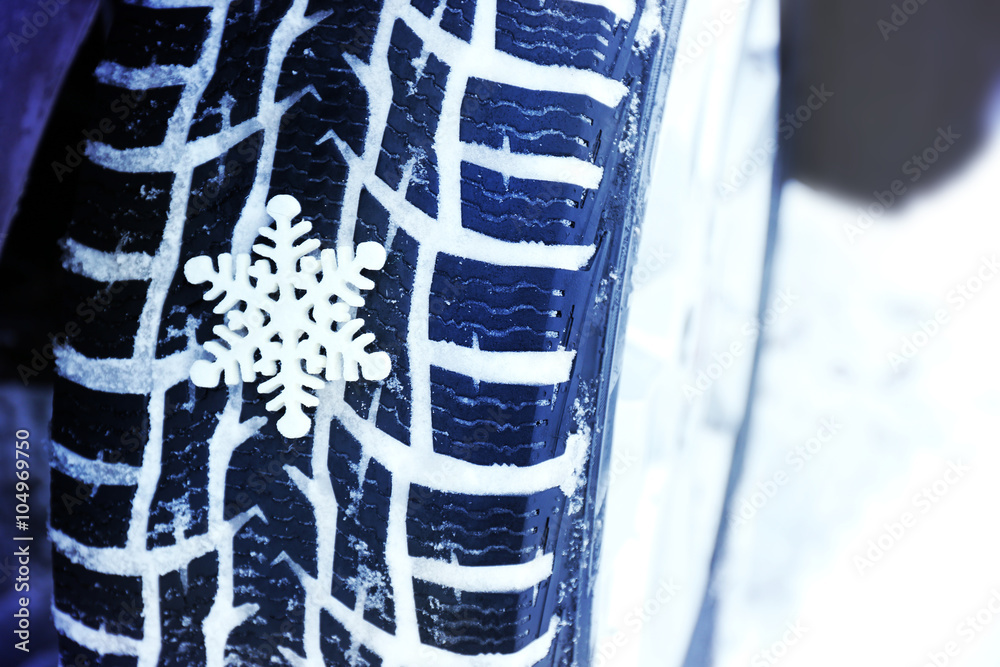 Winter tires in snow with snowflake, closeup Winter tires in snow with snowflake, closeup