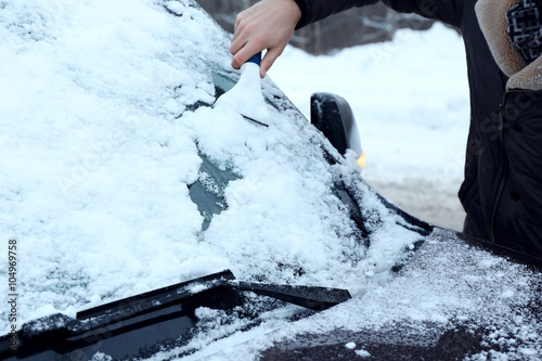 Removing snow from car windshield, closeup
