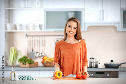 Young woman with fresh vegetables at table in the kitchen