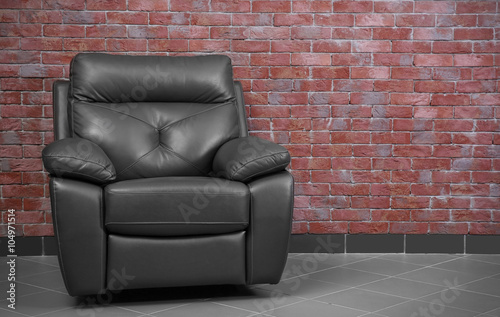 Brown leather armchair against brick wall background