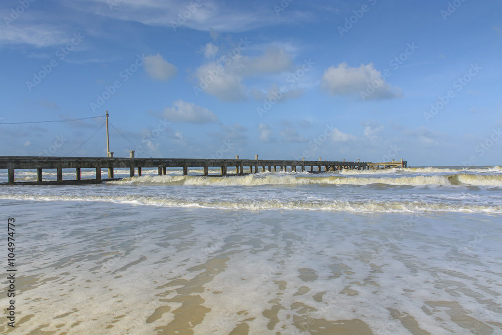 the bridge on piles in port and turquoise water with waves.