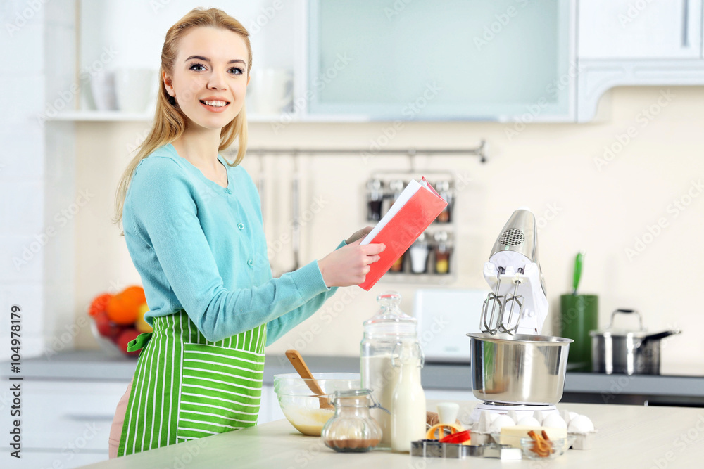 Young woman using a notebook to follow a recipe Young woman using a notebook to follow a recipe
