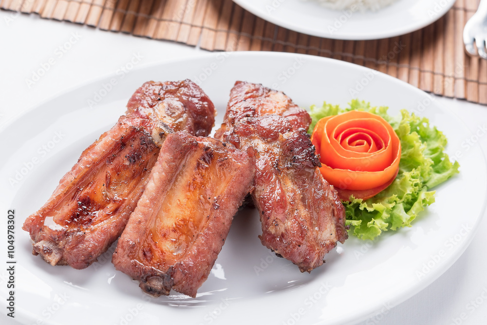fried pork spare ribs on the white dish with a rose make from tomato on the side