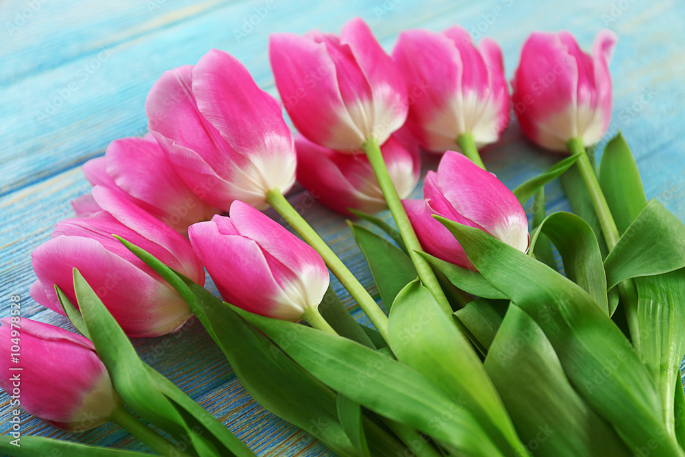 Fototapeta premium Fresh pink tulips on a wooden table, close up