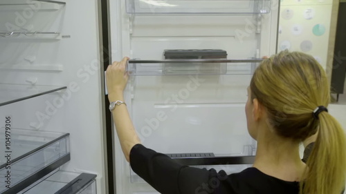 This video shows a lady who is lifting a side shelf up in a fridge and then putting it back on its place. Wide-angle shot.
 photo