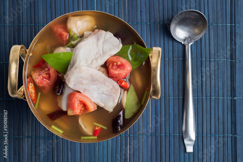 Tom Yum or spicy seabass and lemongrass soup in a brass soup pot